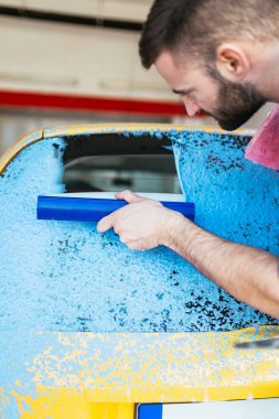 adam araba mavi sünger kullanarak ile köpük temizlik, araba ayrıntılı (veya valeting) kavramı. Seçici odak.