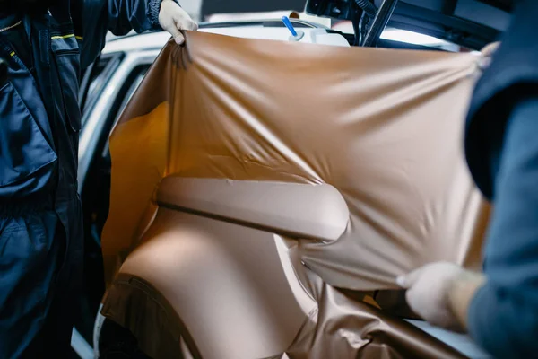 Araba ambalaj uzmanı arabaya vinil folyo ya da film koyuyor. Seçici odak.