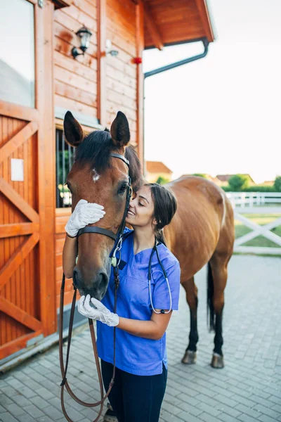 Vet hugging a horse outdoors at ranch.