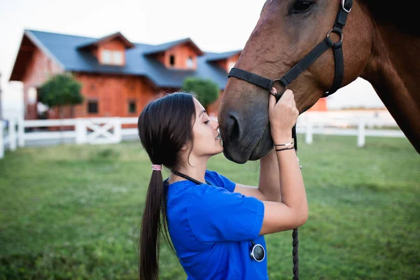 Vet hugging a horse outdoors at ranch.