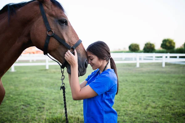 Vet hugging a horse outdoors at ranch.