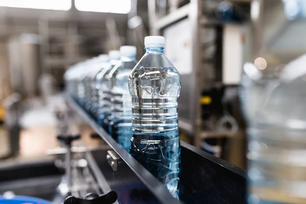 Bottling plant - Water bottling line for processing and bottling pure spring water into blue bottles. Selective focus.