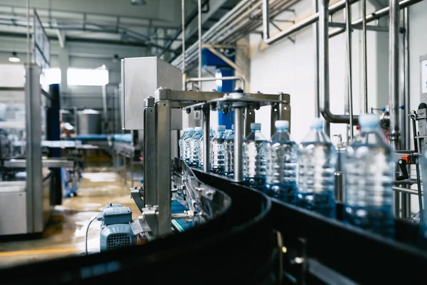 Bottling plant - Water bottling line for processing and bottling pure spring water into blue bottles. Selective focus.