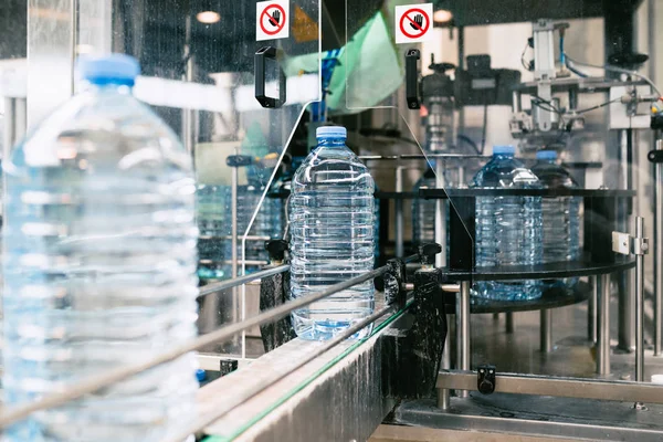 瓶詰め工場 純泉水をブルーボトルに加工および瓶詰めするための水ボトリングライン 選択的焦点 — ストック写真