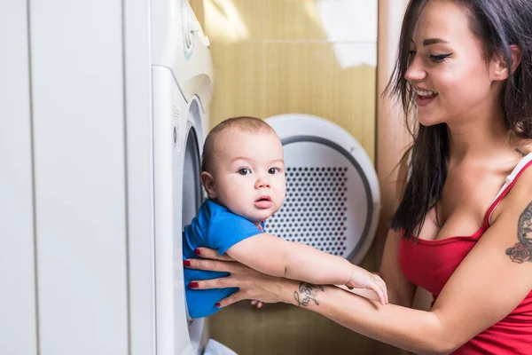Mother taking out her cute little baby boy out of washing machine