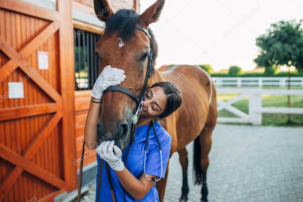 Vet hugging a horse outdoors at ranch. 