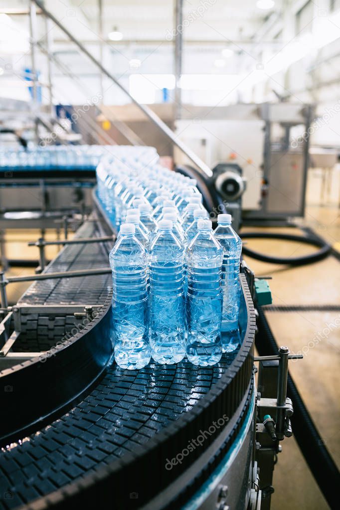 Bottling plant - Water bottling line for processing and bottling pure spring water into blue bottles. Selective focus. 