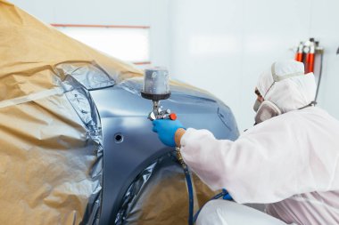 Koruyucu giysi ve sprey kompresör kullanarak maske resim araba olan adam. Seçici odak.