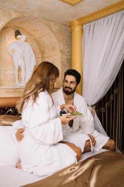 Güzel genç çift zevk ve Spa merkezinde rahatlatıcı ve meyve yatakta kahvaltı