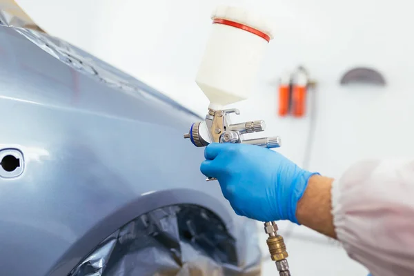 Koruyucu giysi ve sprey kompresör kullanarak maske resim araba olan adam. Seçici odak.