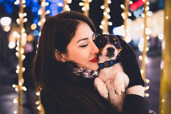 通りのクリスマスイブの中に犬を持つ若い女性 — ストック写真