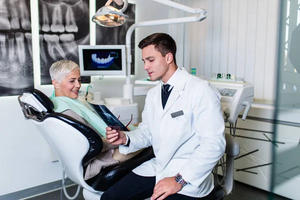 Dentista Sorrindo Bonito Que Olha Imagem Raio Seu Paciente Sênior — Fotografia de Stock