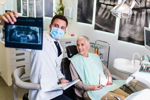 Hezký Usměvavý Zubař Při Pohledu Rentgenový Snímek Své Starší Pacientky — Stock fotografie