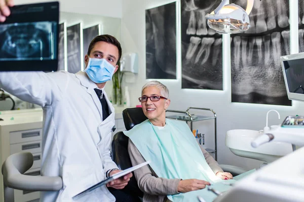 Dentista Sorrindo Bonito Que Olha Imagem Raio Seu Paciente Sênior — Fotografia de Stock