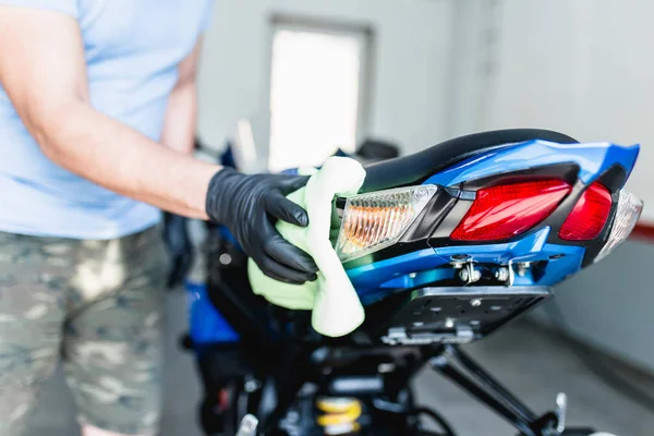 A man cleaning motorcycle with cloth. Selective focus.