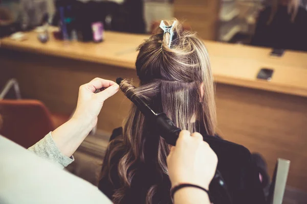 Beautiful hairstyle of young woman after dying hair and making highlights in hair salon.