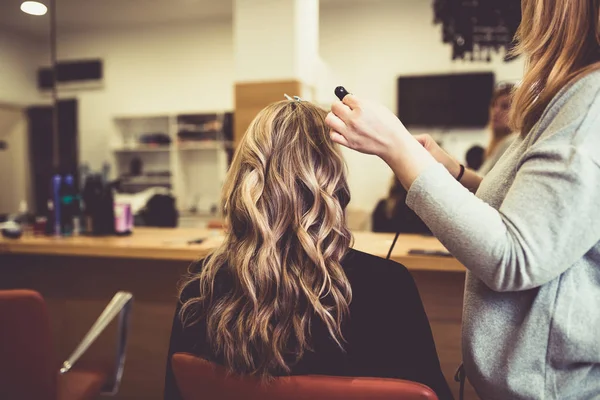 Beautiful hairstyle of young woman after drying hair and making highlights in hair salon.