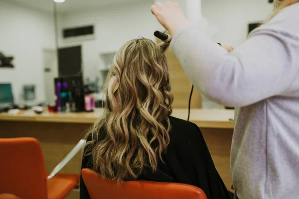 Beautiful hairstyle of young woman after dying hair and making highlights in hair salon.