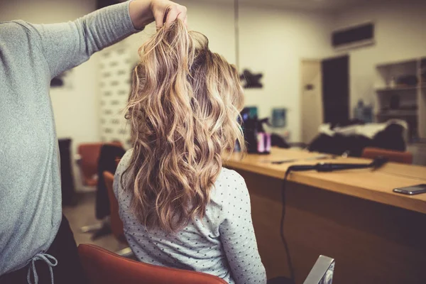 Beautiful hairstyle of young woman after drying hair and making highlights in hair salon.