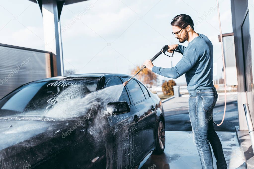 Car washing. Cleaning car using high pressure water. 