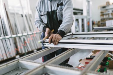 Alüminyum ve Pvc pencere ve kapı üretimi için fabrika. Pvc kapı ve pencereleri monte eden el işçisi. Seçici odaklama. 