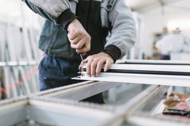 Alüminyum ve Pvc pencere ve kapı üretimi için fabrika. Pvc kapı ve pencereleri monte eden el işçisi. Seçici odaklama. 