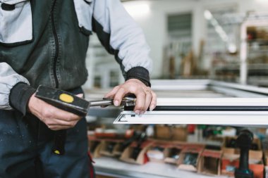 Alüminyum ve Pvc pencere ve kapı üretimi için fabrika. Pvc kapı ve pencereleri monte eden el işçisi. Seçici odaklama. 