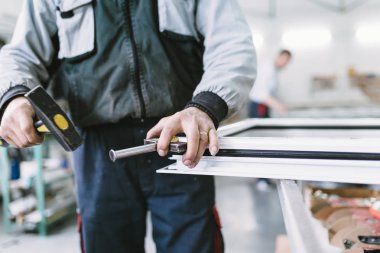 Alüminyum ve Pvc pencere ve kapı üretimi için fabrika. Pvc kapı ve pencereleri monte eden el işçisi. Seçici odaklama. 