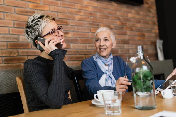 カフェバーに座っているシニアマザーや中年の娘と一緒にレストランに座って 会話を楽しむ — ストック写真