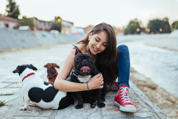 Dog walker with dogs enjoying outdoors next to city river.