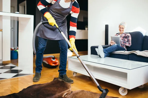 Bonito Marido Limpeza Casa Enquanto Sua Esposa Grávida Relaxando Sofá — Fotografia de Stock