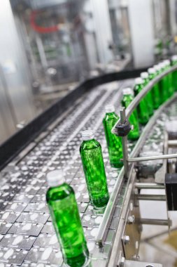 Şişeleme tesisi - Yeşil cam şişeler içine saf kaynak suyu işleme ve şişeleme için su şişeleme hattı. Seçici odaklama. 