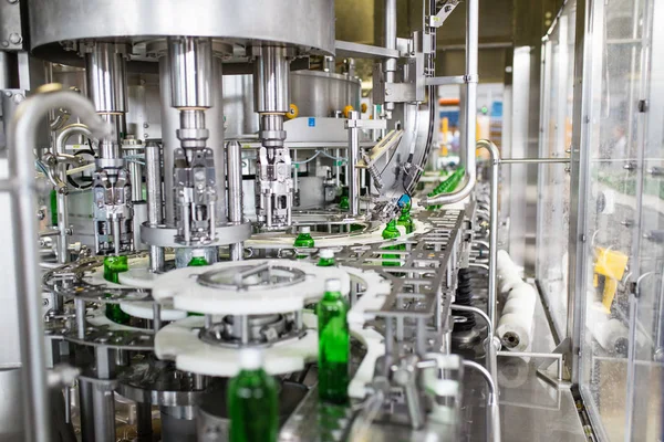 Bottling plant - Water bottling line for processing and bottling pure spring water into green glass bottles. Selective focus.