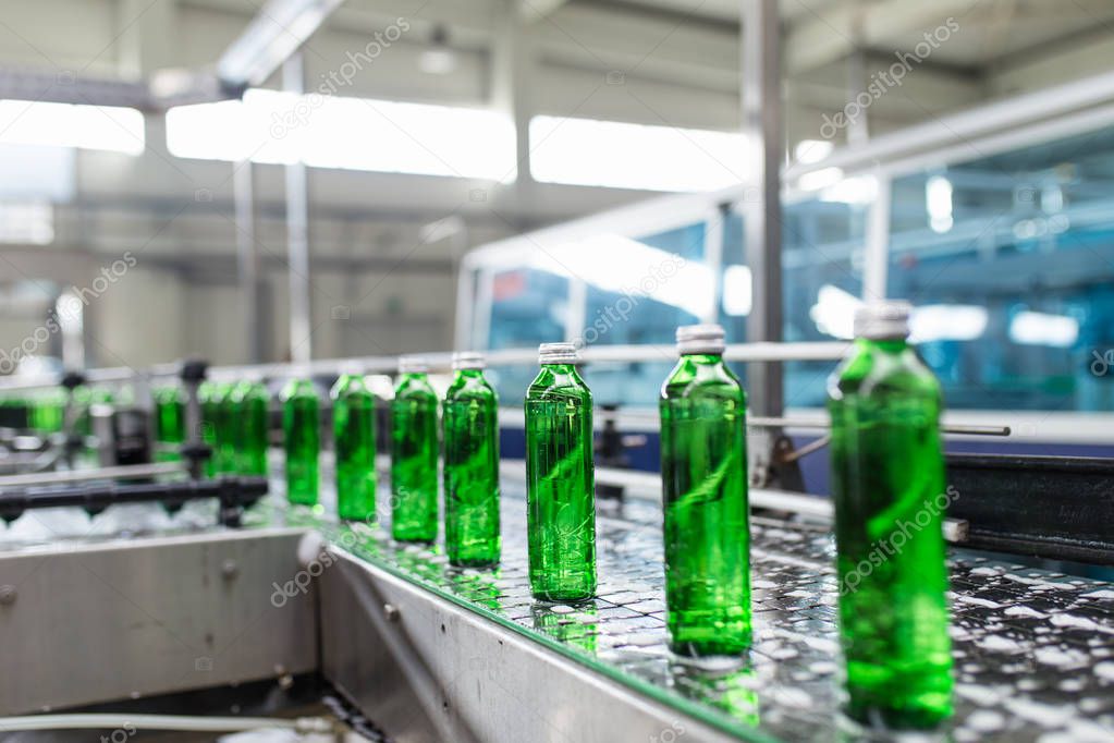Bottling plant - Water bottling line for processing and bottling pure spring water into green glass bottles. Selective focus. 