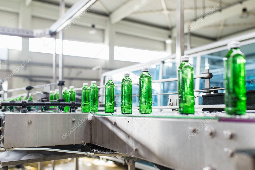Bottling plant - Water bottling line for processing and bottling pure spring water into green glass bottles. Selective focus. 
