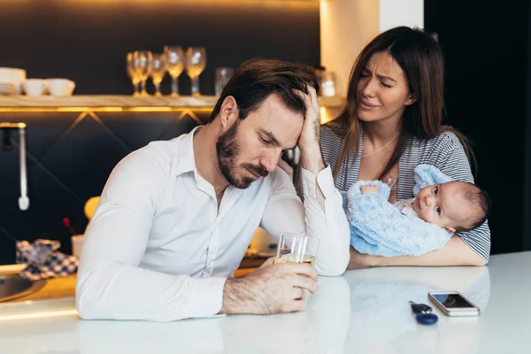 Family violence -  nervous man arguing with his wife while she holding their baby.