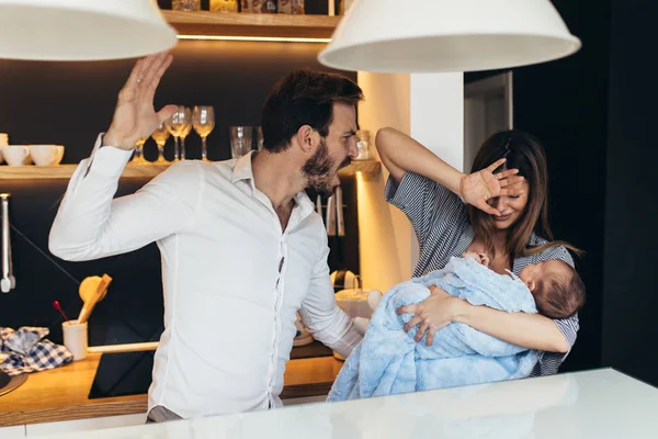 Family violence -  nervous man arguing with his wife while she holding their baby.