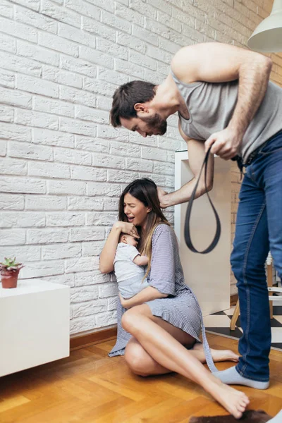 Family violence -  nervous man arguing with his wife while she holding their baby.