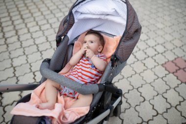 Dışarıda at arabasında yatarken oyuncaklarla oynayan sevimli bir çocuk.