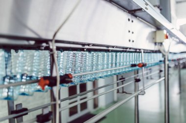 Şişeleme tesisi - Şişelere gazlı suyun işlenmesi ve şişelenmesi için su şişeleme hattı. Seçici odaklama. 