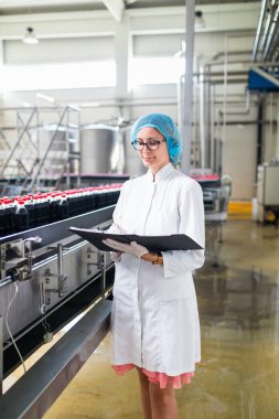 Şişeleme fabrikasındaçalışan kadın işçi sevkiyatöncesi meyve şişelerini kontrol ediyor. Denetim kalite kontrolü. 