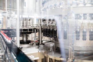 Şişeleme fabrikası, şişelere meyve suyu işlemek ve şişelemek için kullanılıyor. Seçici odak. 