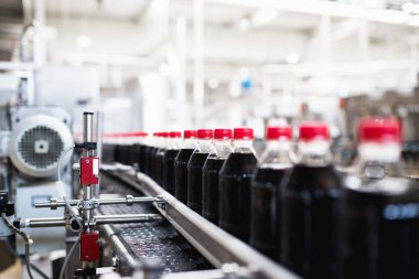 Bottling factory - Black juice bottling line for processing and bottling juice into bottles. Selective focus.  clipart