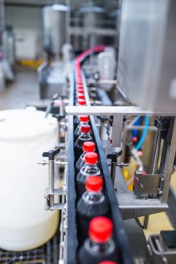 Şişeleme fabrikası, şişelere meyve suyu işlemek ve şişelemek için kullanılıyor. Seçici odak. 