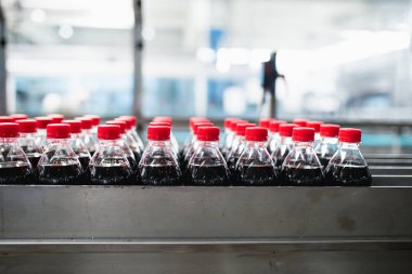 Şişeleme fabrikası, şişelere meyve suyu işlemek ve şişelemek için kullanılıyor. Seçici odak. 