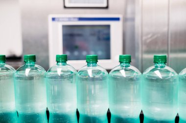 Şişeleme tesisi - Şişelere gazlı suyun işlenmesi ve şişelenmesi için su şişeleme hattı. Seçici odaklama. 