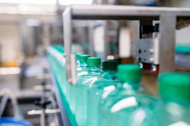 Şişeleme tesisi - Şişelere gazlı suyun işlenmesi ve şişelenmesi için su şişeleme hattı. Seçici odaklama. 