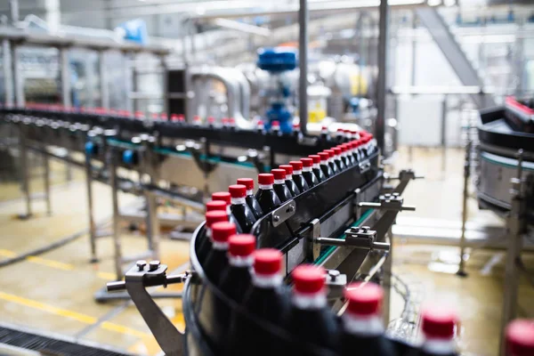 Bottling factory - Black juice bottling line for processing and bottling juice into bottles. Selective focus.