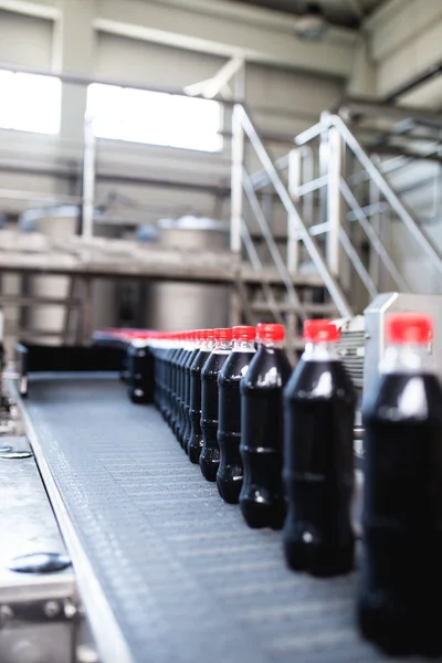 Bottling factory - Black juice bottling line for processing and bottling juice into bottles. Selective focus.