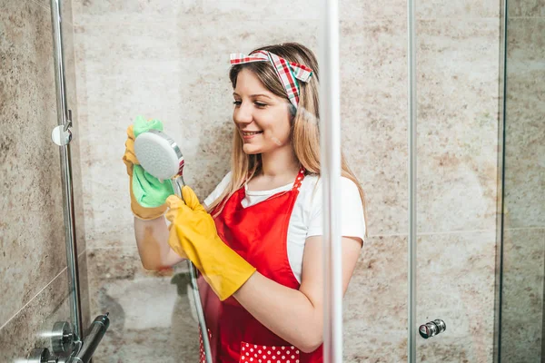 Young and happy woman cleaning house bathroom.